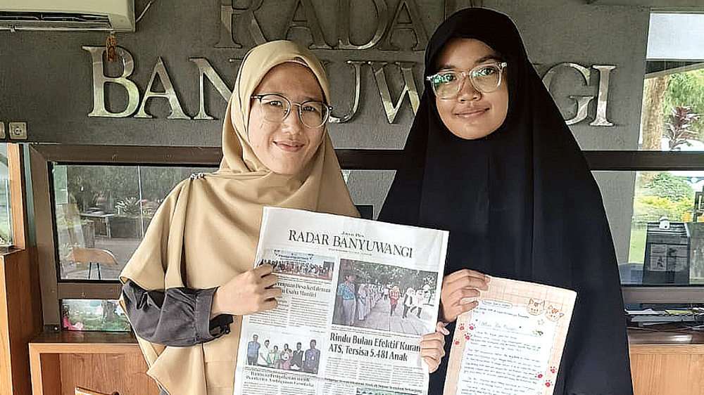 Fatiha Yasmin Azzahra (kanan) didampingi Wali Kelas 7D SMP AL Irsyad Banyuwangi Fava Nurbaiti menunjukkan karya yang diikutkan Lomba Menulis Surat Untuk Bupati di Grha Pena Banyuwangi, Selasa (18/11).