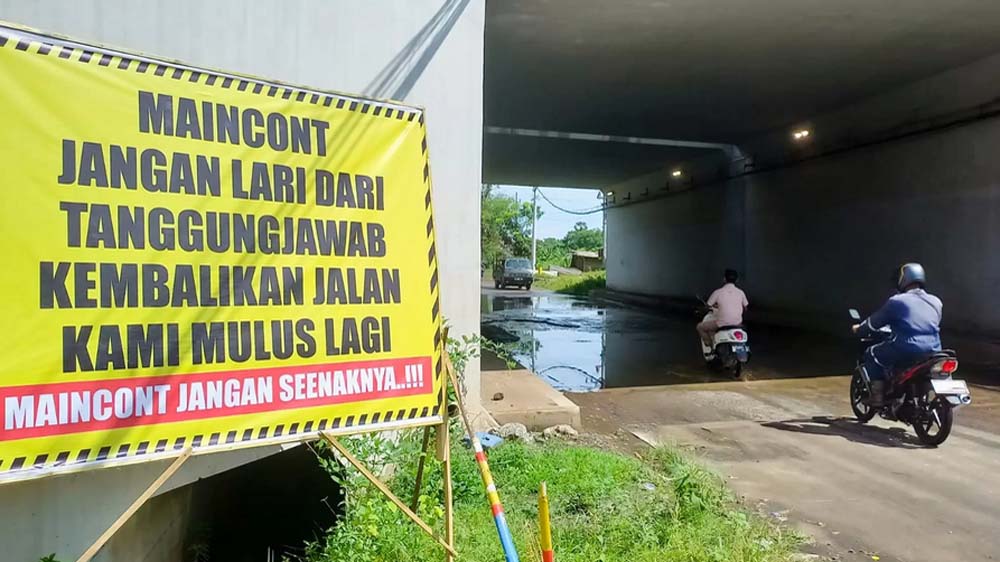 Banner protes terlihat dipasang di tepi jalan rusak di bawah Underpass Tol Probowangi paket 3 masuk Sumberanyar, Paiton, Rabu (10/11).