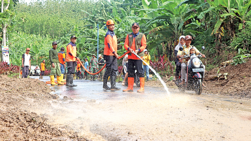 Kalaksa BPBD Danang Hartanto berswama anggota membersihkan sisa material longsor di Gunung Gamping, Desa Sumberagung, Kecamatan Pesanggaran, Minggu (23/11).