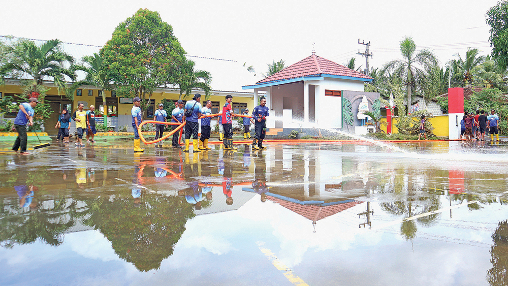 SINERGI: Petugas Gabungan Pemkab Banyuwangi menyemprot lumpur di halaman SDN 3 Sumberagung pada Minggu (23/11).