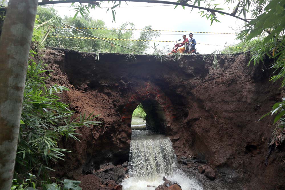 Warga melintas jembatan di Dusun Krajan, Desa Kajarharjo, Kecamatan Kalibaru, Banyuwangi, yang ambrol, Jumat (28/11).