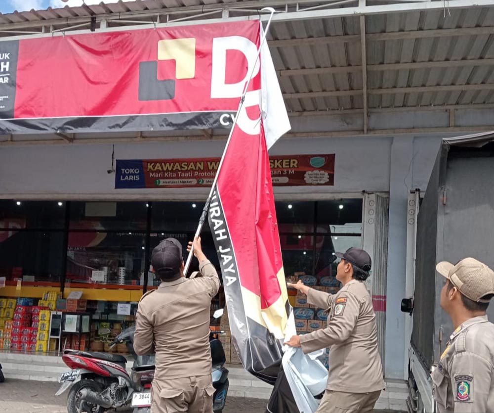 PENCOPOTAN: Banner iklan rokok yang dipasang di zona terlarang ditertibkan petugas Satpol PP di Jalan Raya Desa Sraten, Kecamatan Cluring, Senin (1/12).