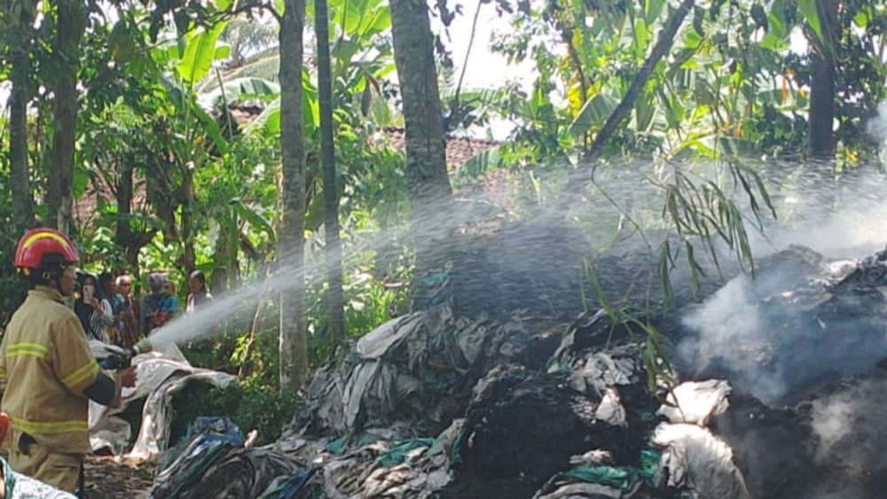 Petugas Damkarmat Sektor Srono memadamkan api yang membakar tumpukan rongsokan di Dusun Sukorjo, Desa Sukomaju, Kecamatan Srono, Senin (1/12).
