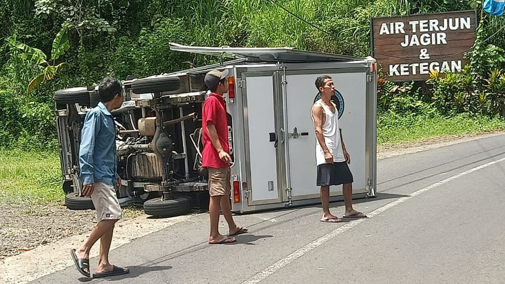 Kondisi mobil box pengangkut MBG setelah terguling di depan pintu masuk wisata air terjun Jagir, Desa Kampunganyar, Kecamatan Glagah, Senin (1/12).