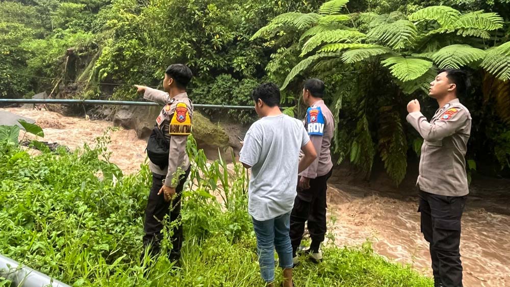 MENGALIR DERAS: Aparat kepolisian memantau arus sungai di lokasi hanyutnya Ponirin, 50, warga Dusun Sumberagung, Desa Sumberbulu, Kecamatan Songgon.
