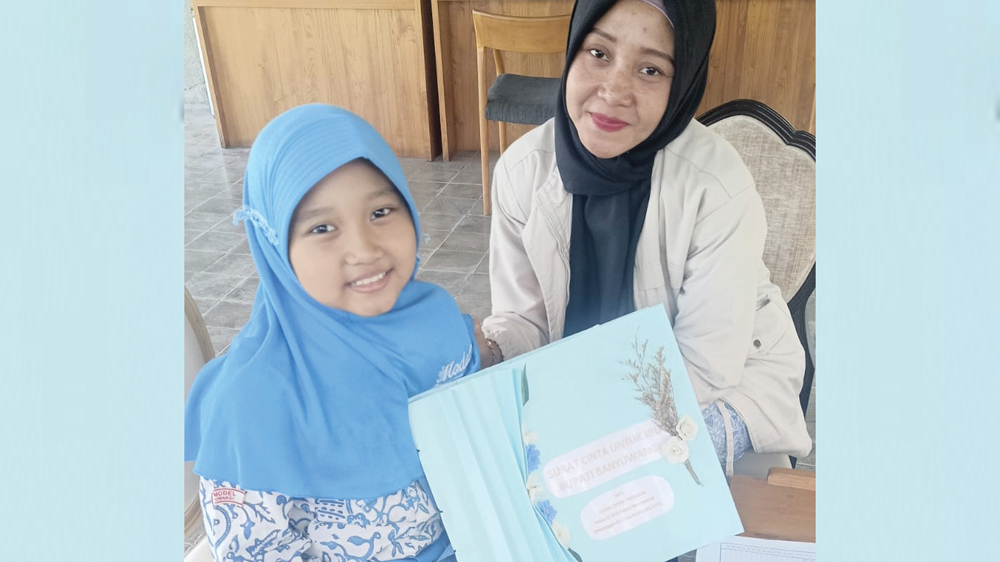 Aysha Zahira Hafiyanda menunjukkan surat untuk bupati hasil kreasinya saat mendaftar di Grha Pena Banyuwangi.