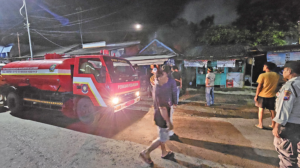 Petugas Damkarmat Bangorejo, kepolisian, bersama warga berusaha memadamkan api yang membakar warung makan di Dusun Kebonrejo, Kebondalem, Bangorejo, Minggu malam (7/12).