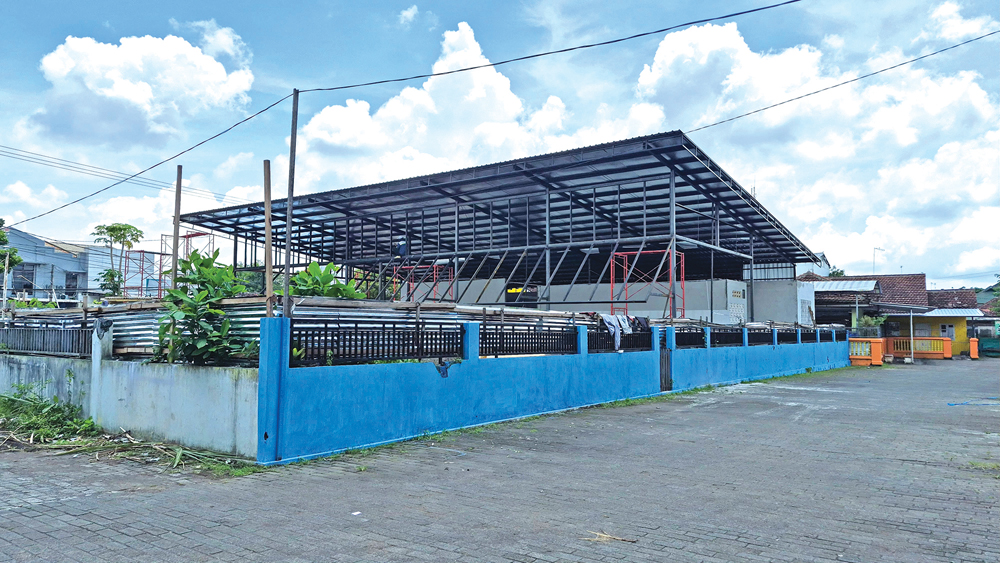 Pekerja menggarap bagian atap bangunan yang diduga untuk kedai mi cepat saji di depan kantor Korsda Genteng, Minggu (7/12).
