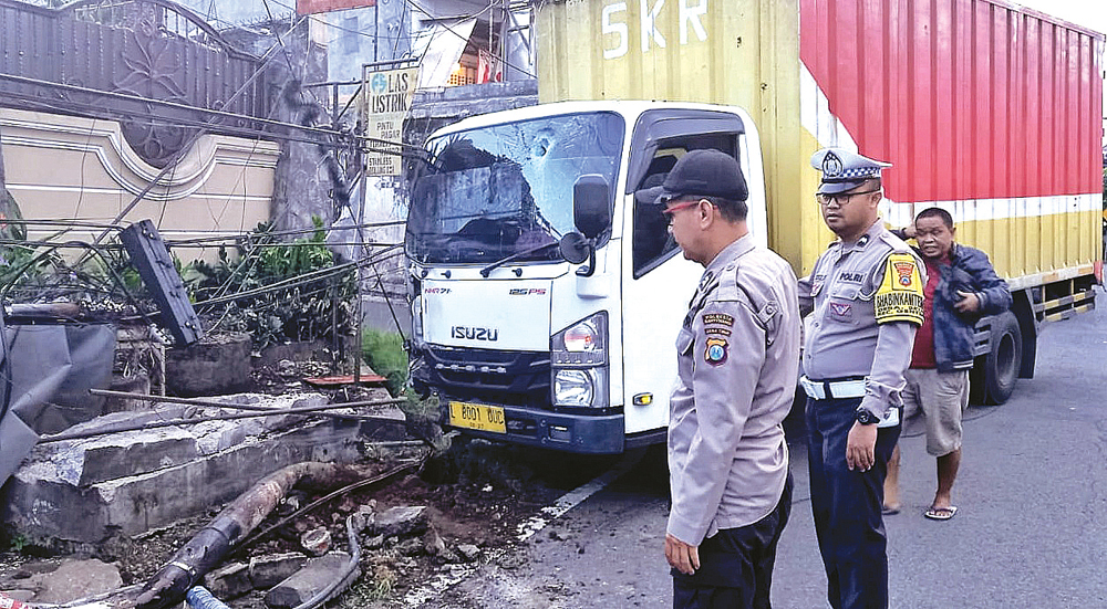 Anggota Unit Lantas Polsek Genteng melihat kondisi truk yang terlibat kecelakaan tunggal di Jalan Gajah Mada Gentengwetan, Kecamatan Genteng, Senin (8/12).