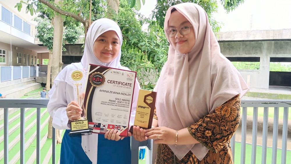 Ayrina Zevania Rizaldy didampingi guru SD Lazuardi Tursina menunjukkan piala dan sertifikat penghargaan gold award Champs Universal Music Festival.