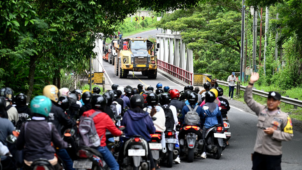 BUKA-TUTUP: Arus lalu lintas di dekat Jembatan Tambong tersendat gara-gara truk muatan alat berat terperosok ke parit.