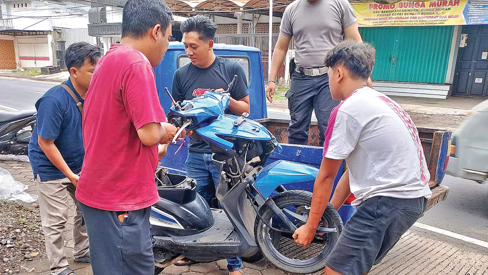 Aparat dibantu warga mengevakuasi sepeda motor yang terlibat kecelakaan di Jalan KH Hasanudin, Dusun Krajan, Desa Genteng Wetan, Genteng, Minggu (21/12).