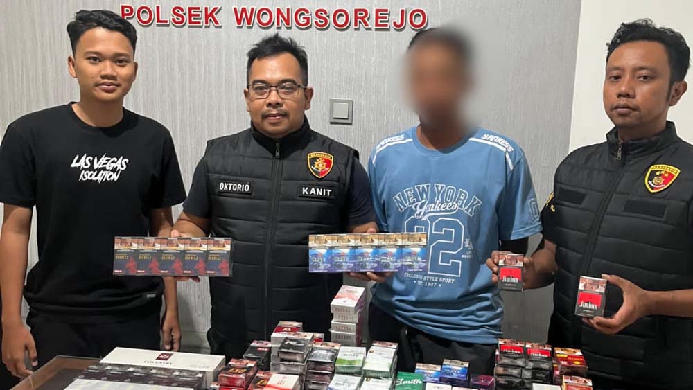 DISITA DARI TOKO KELONTONG: Pj Kanitreskrim Polsek Wongsorejo Aipda Oktorio Wisnu Pradana (dua dari kiri) menunjukkan barang bukti rokok ilegal, Selasa (23/12).