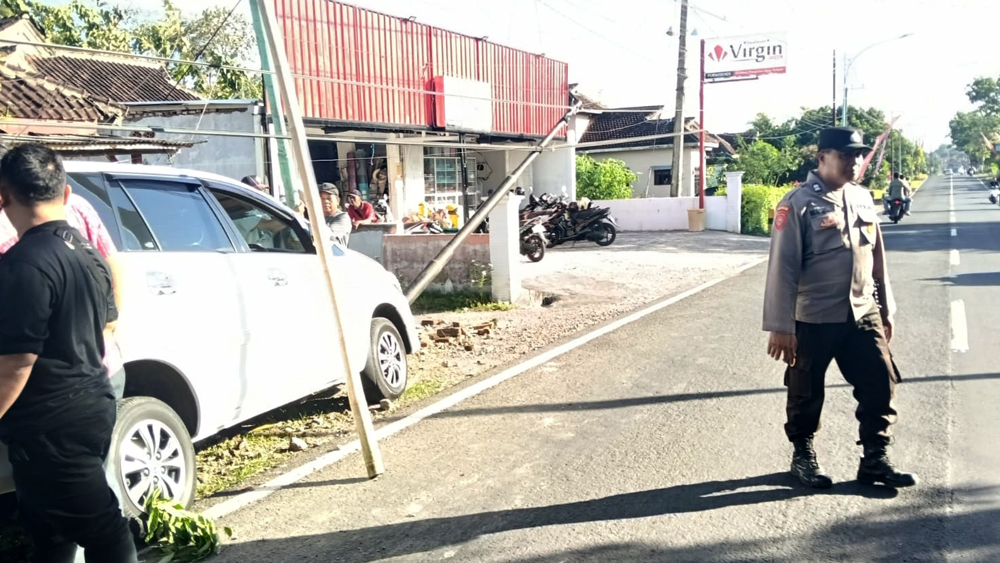 Anggota Polsek Gambiran berada TKP kecelakaan mobil Inova menabrak tiang LPJU di Jalan Raya Desa Purwodadi, Kecamatan Gambiran pada Selasa (23/12).