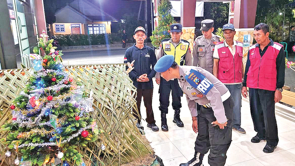 Anggota Polsek Purwoharjo didampingi petugas dari Satgas Bhinneka Tunggal Ika mengecek pohon Natal di Gereja Maria Ratu Para Rasul, Grajagan, Purwoharjo, Rabu (24/12) malam.