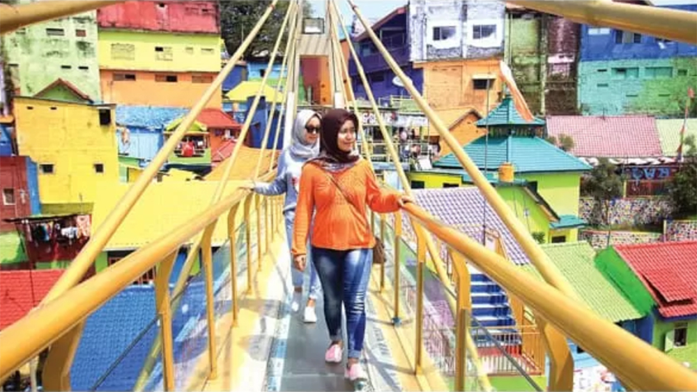 Pengunjung melintasi jembatan yang berada di Kampung Warna-warni di Kelurahan Jodipan, Kecamatan Blimbing, Kota Malang.