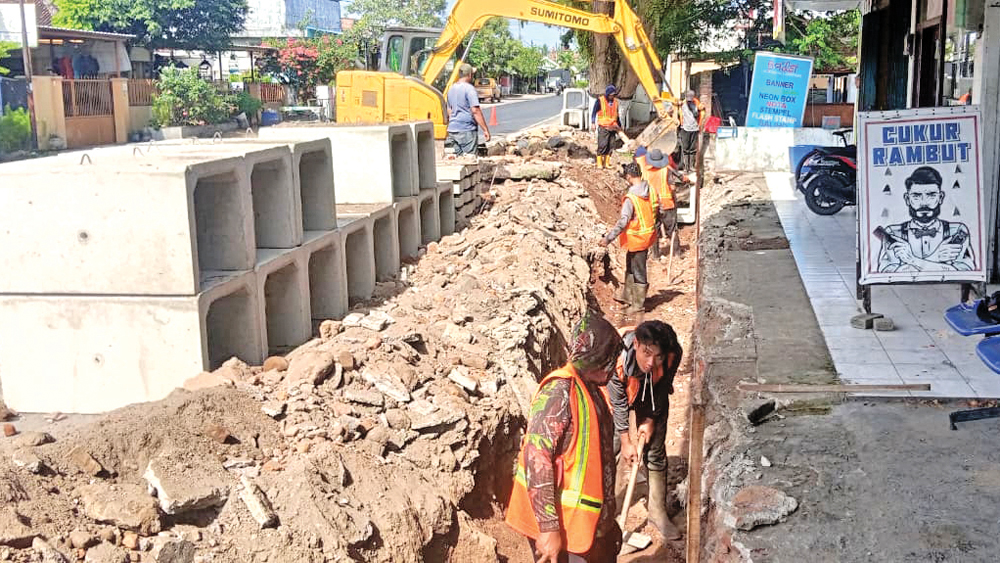 Pekerja mengeruk saluran air di tepi Jalan Raya Desa Lemahbang Dewo, Kecamatan Rogojampi, sebelum dipasangi U-ditch, Selasa (30/12).