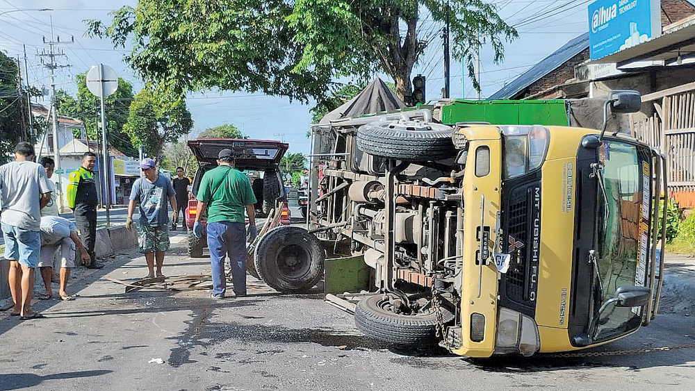 KECELAKAAN TUNGGAL: Polisi dibantu warga melakukan proses evakuasi Truk nopol P 8894 GK yang terguling di Jalan Brawijaya Banyuwangi, Minggu pagi (4/1).