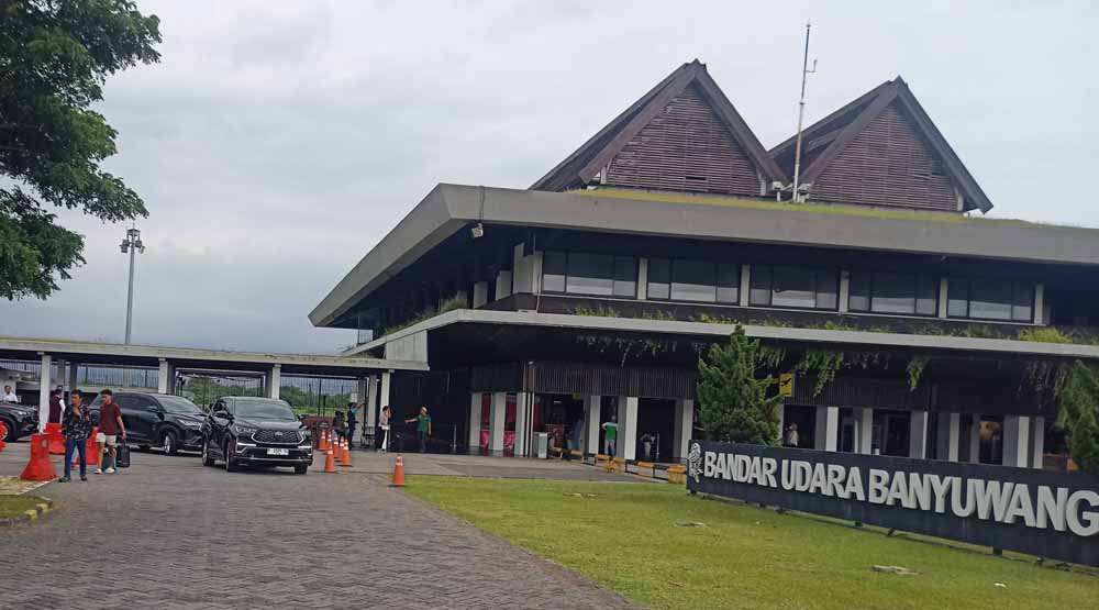 MENENTENG KOPER: Pennguna jasa penerbangan berjalan kaki di area parkir kendaraan Bandara Internasional Banyuwangi, Minggu (4/1).