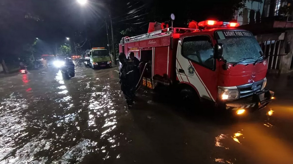 Petugas Damkar Surabaya sedang berjibaku menyedot genangan air yang muncul setelah hujan deras pada Minggu sore (4/1).