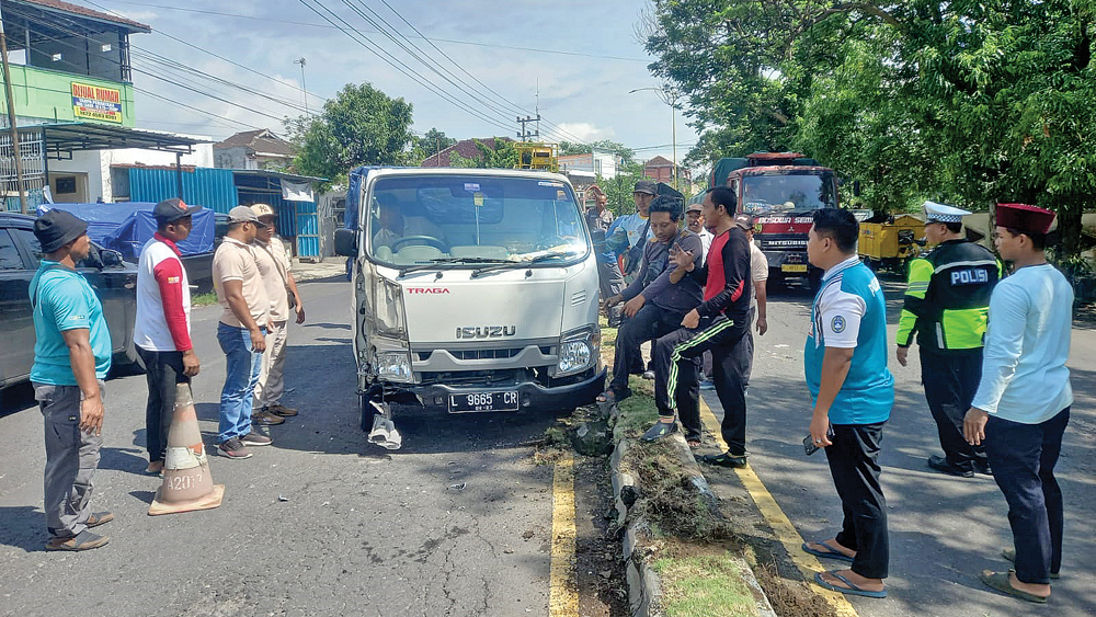 Sejumlah warga dan sopir membantu proses penarikan mobil pikap yang mengalami kecelakaan tunggal di Jalan Raya Brawijaya, Jumat (9/1).