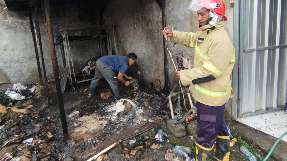 Petugas Damkarmat Sektor Bangorejo padamkan api di tumpukan kardus milik salah satu toko kosmetik di Kecamatan Purwoharjo Minggu (11/1).
