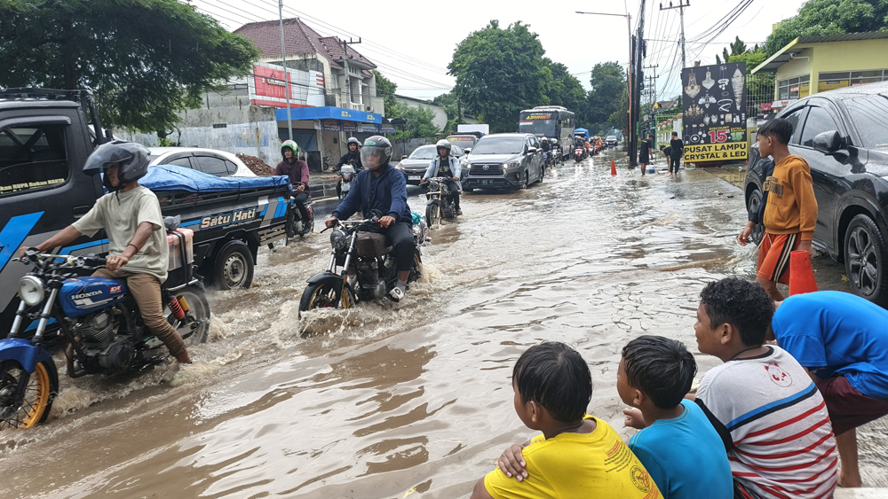 HUJAN LEBAT: Hampir separuh roda sepeda motor tergenang air ketika melintas di Jalan Letjen S. Parman, Banyuwangi Minggu (18/1).