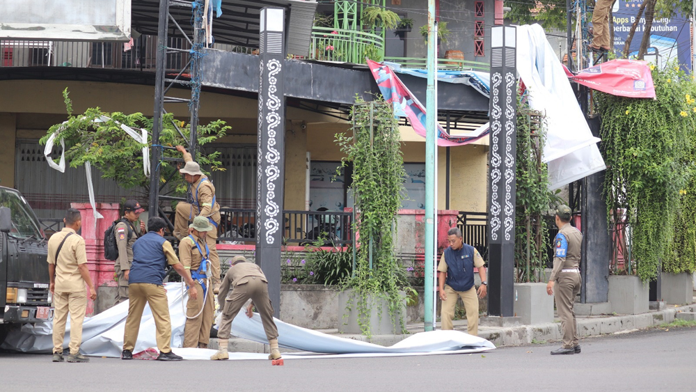 DIBONGKAR: Anggota Satpol PP Banyuwangi membongkar reklame diduga melanggar di Jalan Raya Cungking, Kecamatan Giri, Minggu (18/1).