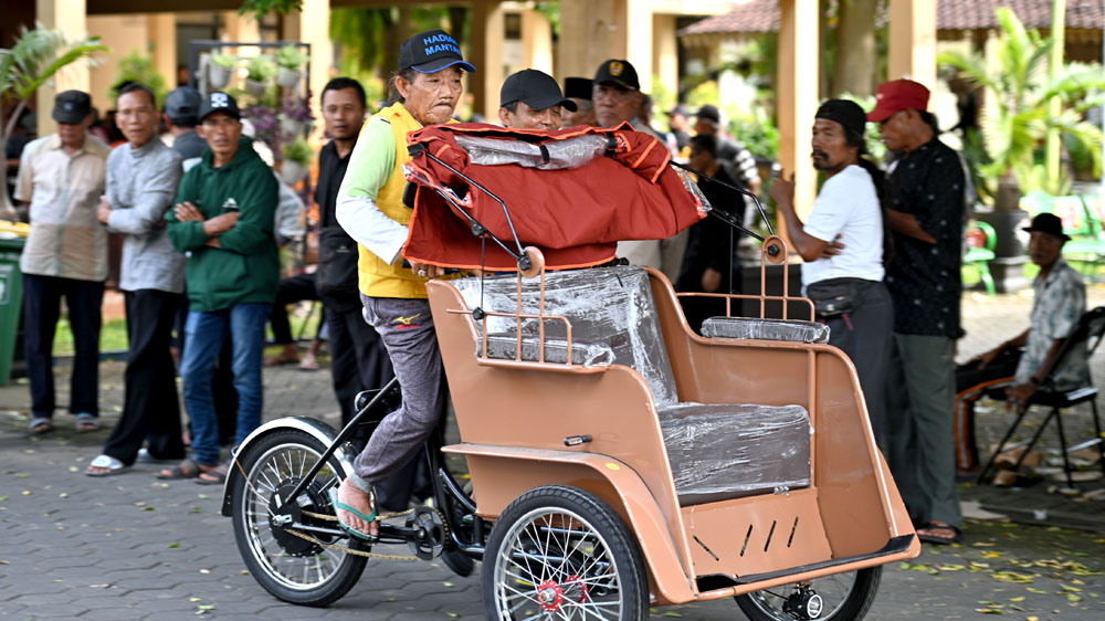 Seorang tukang becak menjajal becak listrik di halaman gedung Korpri Banyuwangi, Selasa (20/1).