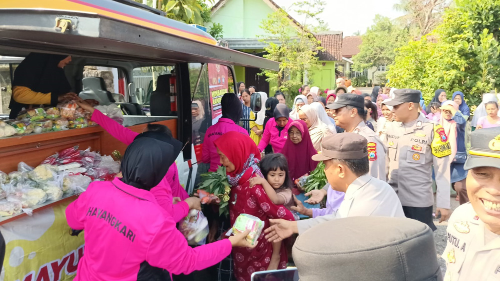 Personel Satuan Binmas Polresta Banyuwangi membagikan sayuran gratis dan kebutuhan pokok lainnya kepada warga Desa Benculuk, Kecamatan Cluring, Jumat (30/1).