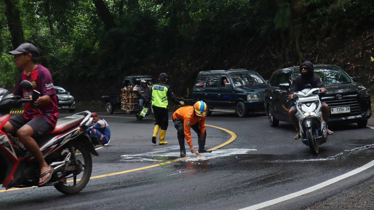 Petugas BPBD Jatim membersihkan ceceran oli di jalur Gumitir,  tepatnya di Dusun Barurejo, Desa Kalibaru Manis, Kecamatan Kalibaru Sabtu (31/1).