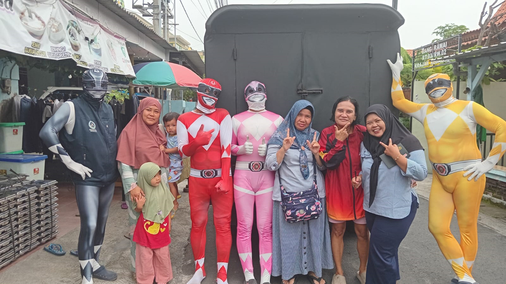 Petugas SPPG berkostum Power Rangers membagikan MBG dengan sasaran kelompok B3 di rumah kader posyandu Kebalenan, Senin (26/1).