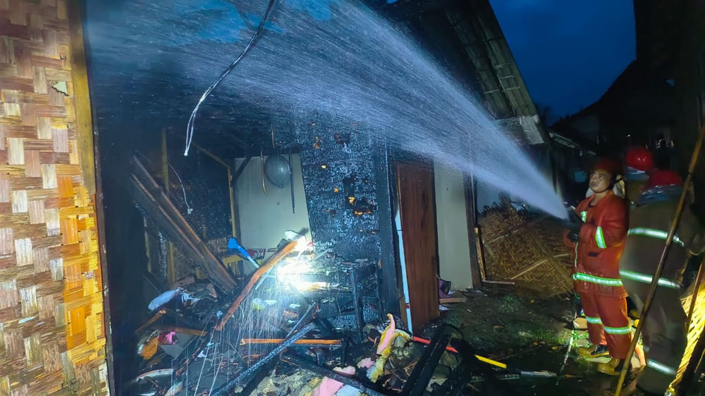 Petugas sedang menyemprotkan air pada rumah yang terbakar di Desa Segobang, Kecamatan Licin, Sabtu (7/2).