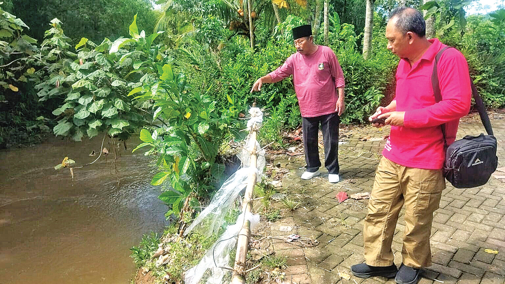 Kepala Desa Sarongan Gunoto meninjau lokasi jalan kampung yang terkikis aliran Sungai, Senin (9/2).