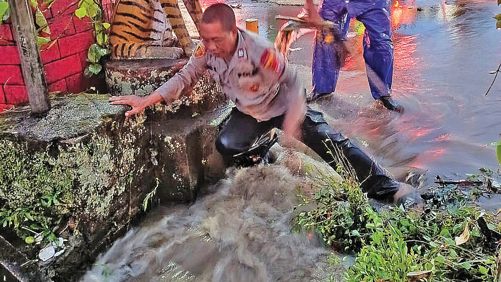 MAMPET: Petugas Polsek Glenmore membersihkan sampah yang menyumbat drainase di sempadan jalan Desa Karangharjo, Kecamatan Glenmore, Senin (9/2).