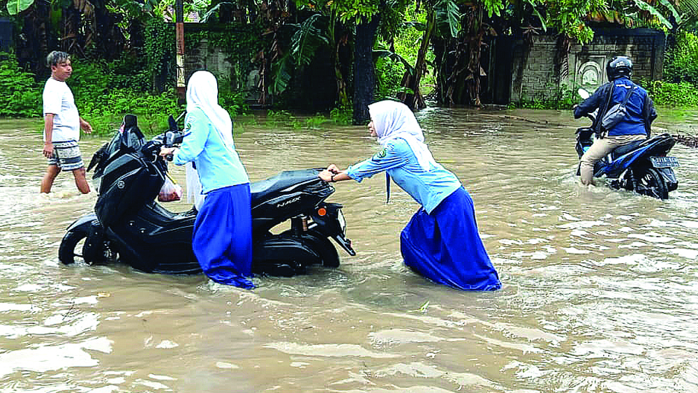 Pengendara sepeda motor mendorong kendaraannya yang macet lantaran terkena genangan air di Jalan Raya Desa Sumberberas, Kecamatan Muncar, Rabu (11/2).