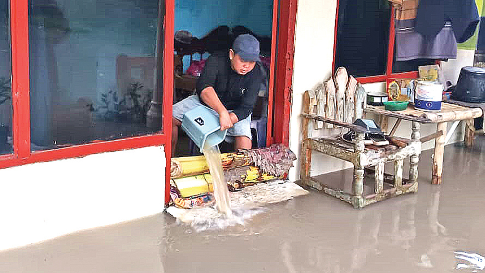 Warga sedang menguras air yang masuk di rumahnya Desa Tambakrejo, Kecamatan Muncar pada Rabu (11/2).