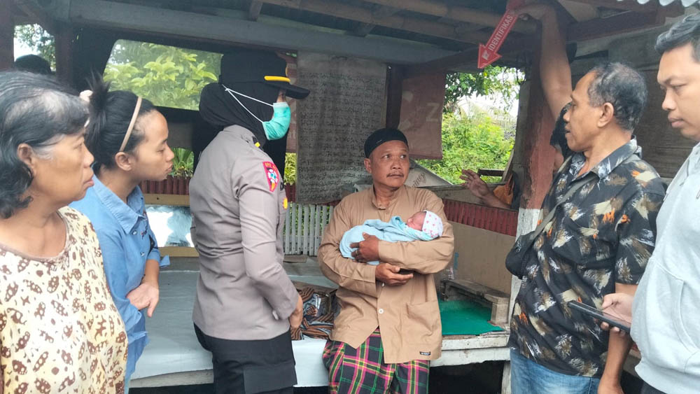 Ketua RT Faizin menggendong bayi yang dibuang di poskamling depan rumahnya di Kelurahan Sumberrejo, Banyuwangi, Jumat (13/2).