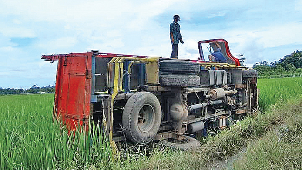 Truk yang melintas di jalan licin usai diguyur hujan terguling di persawahan Desa Sumberberas, Kecamatan Muncar, Kamis (12/2).