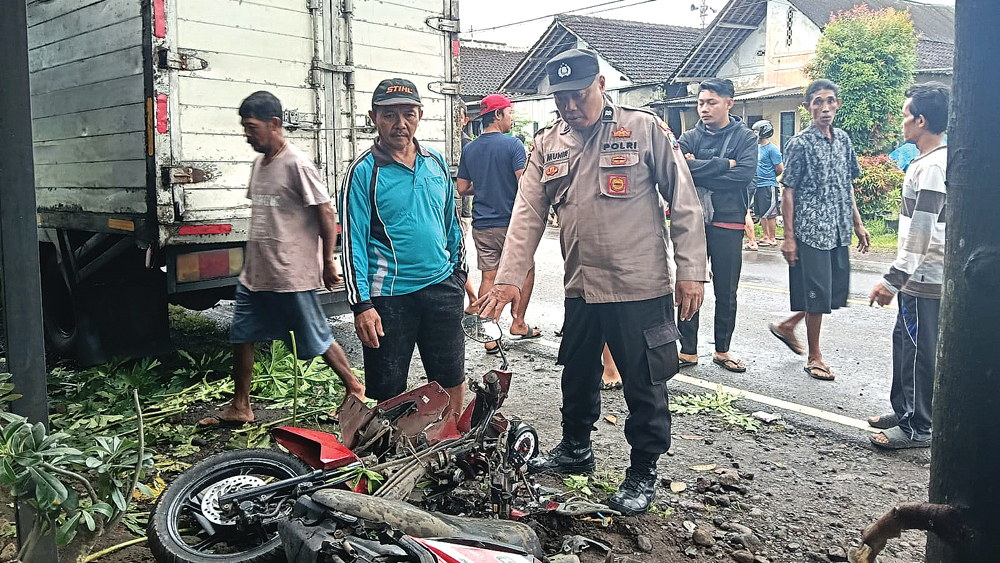Petugas Unit Lantas Polsek Gambiran mengecek lokasi kejadian serta dua unit kendaraan yang terlibat kecelakaan lalu lintas di Jalan Raya Desa/Kecamatan Gambiran, Jumat (13/2).