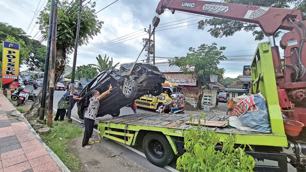 Mobil Toyota Avanza P 1501 VV yang rusak setelah menabrak pohon angsana di depan Polsek Genteng diangkut truk towing, Jumat (20/2).