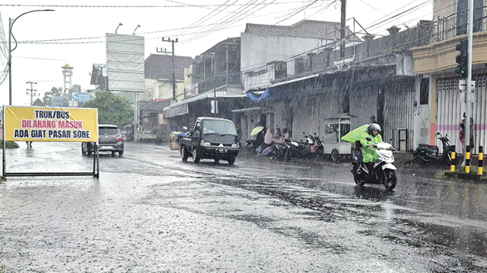 DIGUYUR HUJAN: Sejumlah melintas di Jalan Gajah Mada, Genteng, saat hujan melanda kawasan tersebut pada Selasa (3/3).