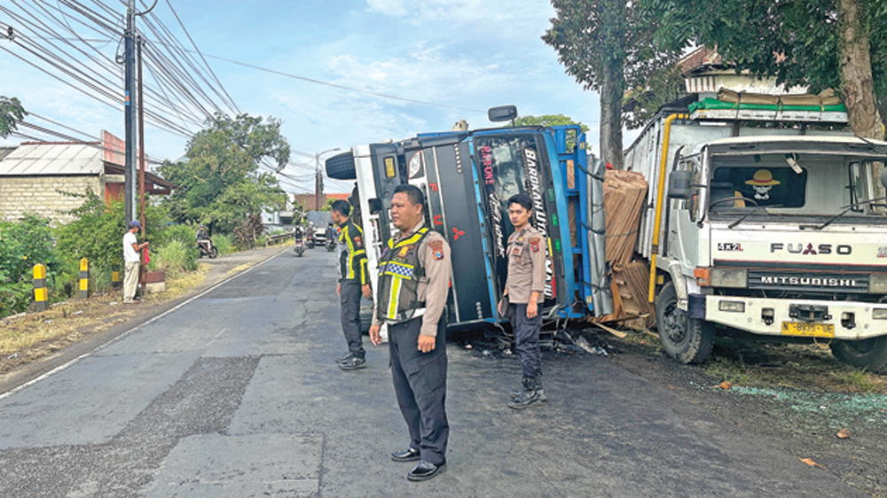 Anggota Unit Lantas Polsek Kalibaru mengatur arus lalu lintas di lokasi truk terguling di jalan raya Dusun Wadung Kamidin, Desa Tulungrejo, Kecamatan Glenmore, Rabu (4/3).