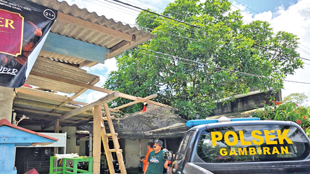 Petugas sedang mengecek rumah milik lansia di Kecamatan Gambiran yang rusak diterjang angin kencang, Kamis (5/3).