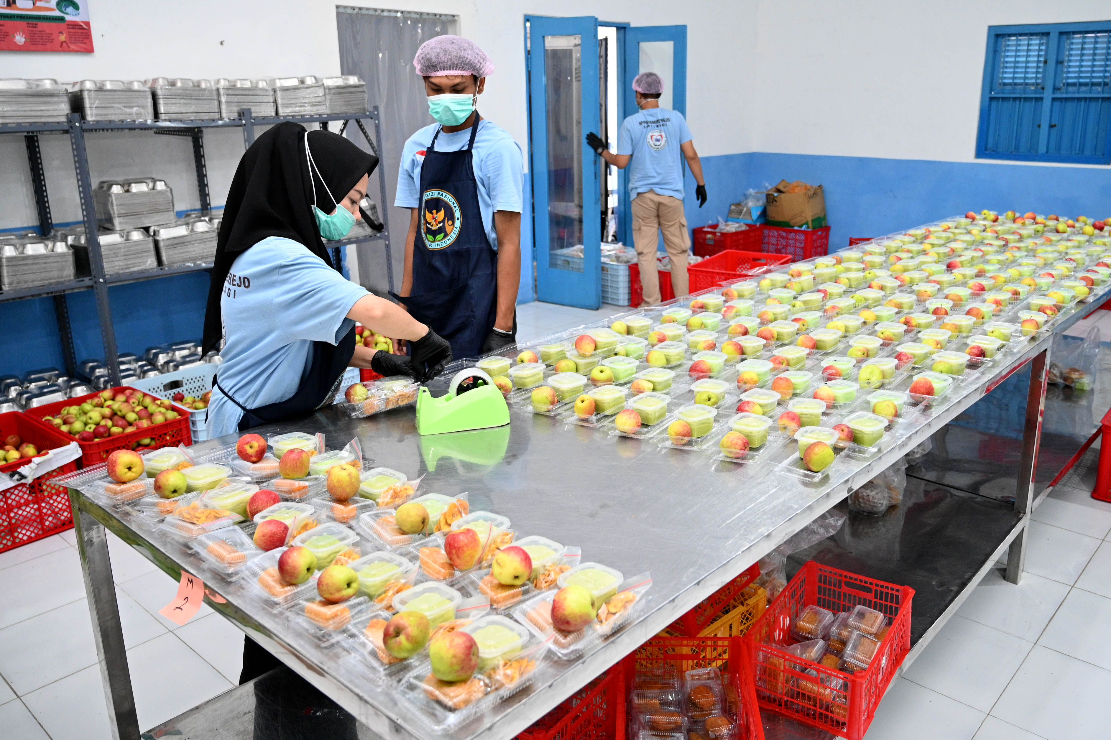 STANDAR KEBERSIHAN: Tim dapur SPPG Sumberrejo, Banyuwangi, saat mengemas menu makanan untuk didistribusikan ke sekolah-sekolah sesuai rute yang telah ditentukan.