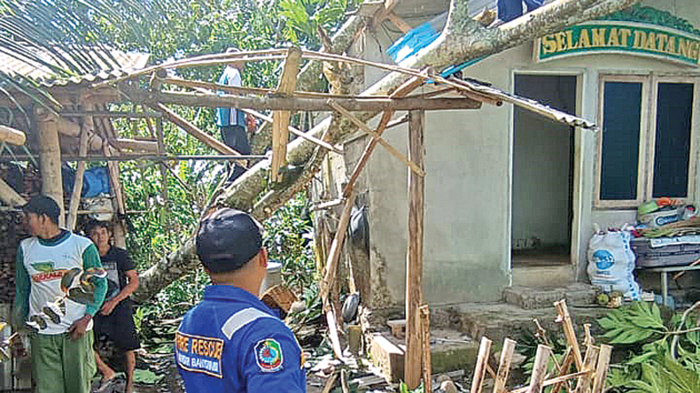 Tim gabungan melakukan memotong batang dan dahan pohon yang menimpa rumah warga di Kecamatan Srono pada Kamis (5/3).