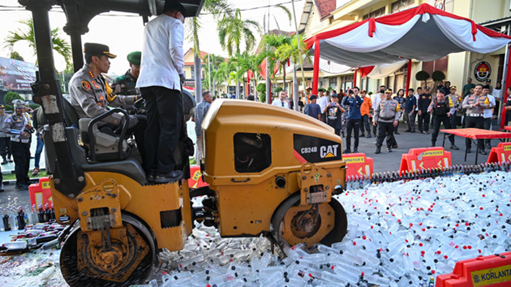 Kapolresta Banyuwangi Kombespol Rofiq Ripto Himawan bersama Wabup Mujiono naik selender menggilas ribuan botol miras di halaman Mapolresta Banyuwangi, Kamis (12/3).