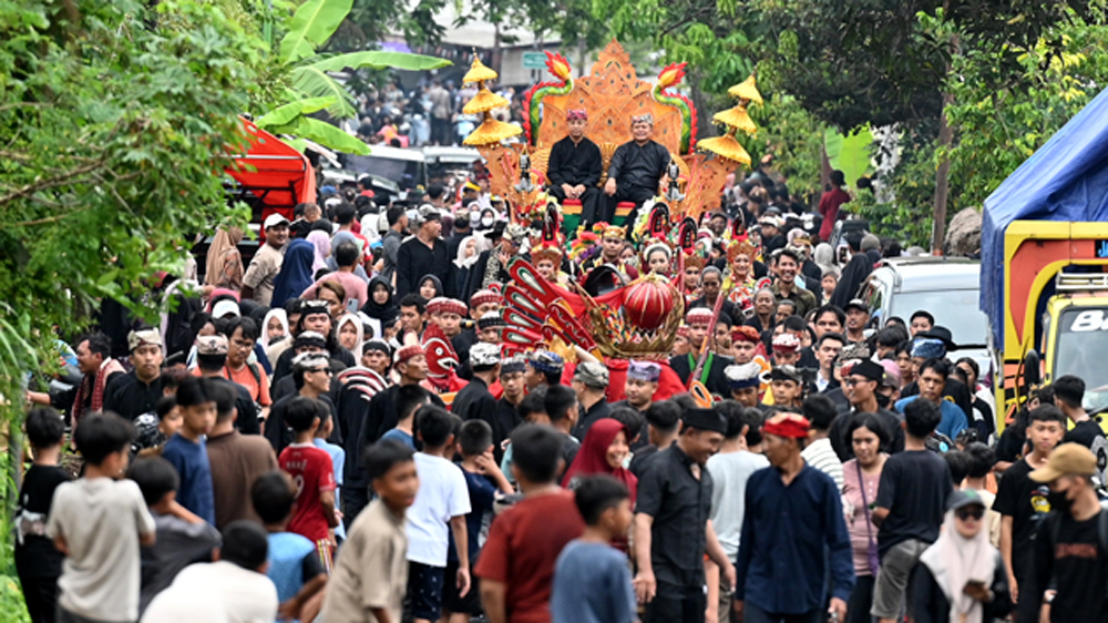 Plt Kepala Disbudpar Hartono (kiri) dan Kades Kemiran Mohammad Arifin mengikuti arak-arakan Barong Ider Bumi di Desa Kemiren, Kecamatan Glagah, pada Minggu (22/3).