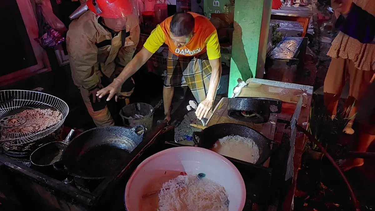 Petugas Damkarmat sedang memadamkan api yang membakar peralatan dapur warung darplok Sritanjung di Kelurahan Temenggungan, Kamis malam (26/3). (Damkarmat Banyuwangi)