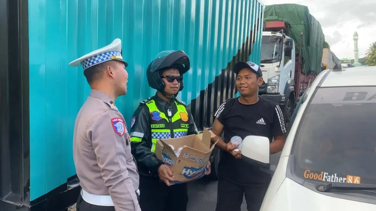 Anggota Satlantas membagikan air mineral kepada para pengendara yang terjebak macet di jalan arteri menuju Pelabuhan Ketapang, Rabu (1/4). (Satlantas Polresta Banyuwangi)